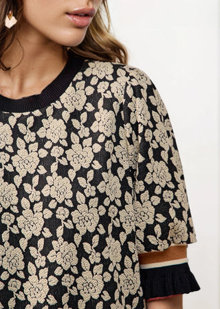 Woman wearing a black floral dress with a plain white background