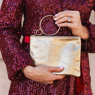 Woman holding the Gold Rush metallic pouch by its circular bracelet handle
