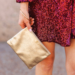 Woman carrying the Gold Rush metallic pouch with a sequin party dress