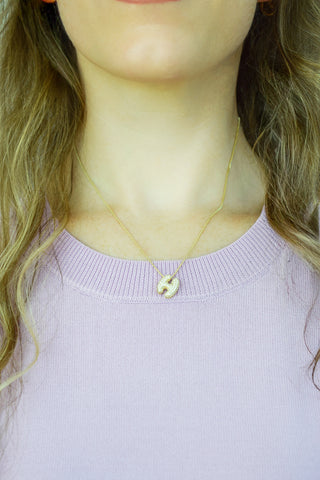 Delicate gold initial S necklace worn close to the neck
