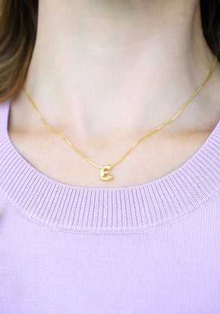 Single gold initial E necklace worn at the collarbone