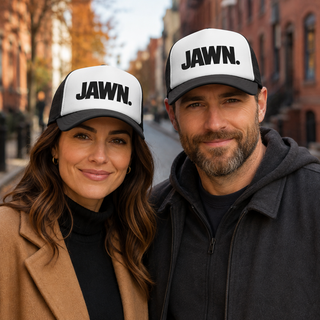 Woman and man wearing black-and-white JAWN. trucker hats on a Philadelphia street