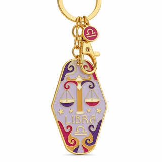 A gold-tone Libra zodiac keychain featuring a coffin-shaped charm with a lavender background, gold Libra symbol, and red and purple decorative accents.