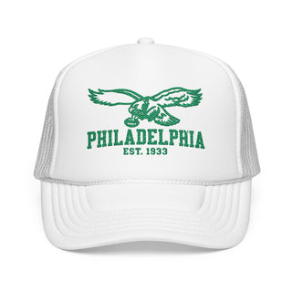 A white trucker hat with green embroidered graphics on the front panel, featuring an eagle and the text 'PHILADELPHIA EST. 1933'.
