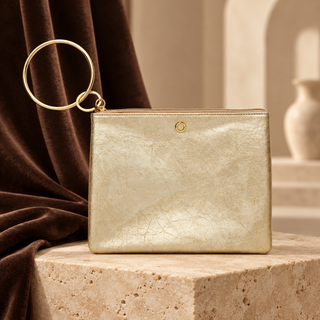 Gold Rush metallic Big O bracelet pouch with circular gold handle on cream stone