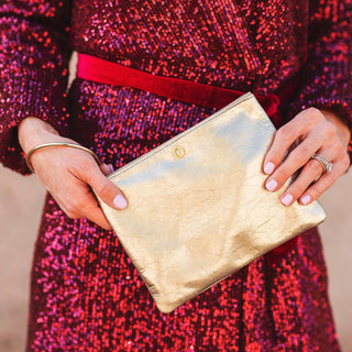 Close lifestyle view of the Gold Rush bracelet pouch against a sequin dress