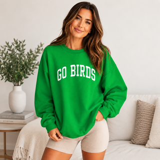 Woman wearing bright green GO BIRDS embroidered crewneck sweatshirt in a warm cream interior