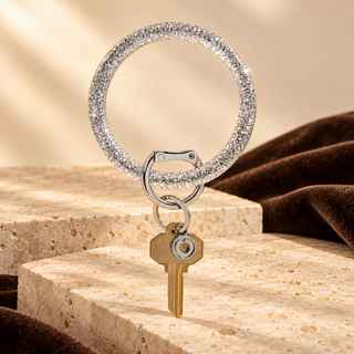 Resin Big O Disco Ball Sparkle bracelet keychain with silver hardware and a brass key on cream stone