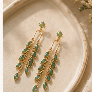 Verdant Cascade earrings styled on a cream jewelry tray